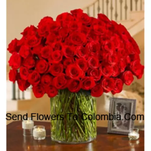 100 crvenih ruža s nekim paprati u velikoj staklenoj vazi
